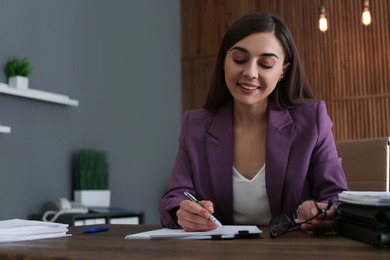 Photo of Beautiful businesswoman working with documents at table in office