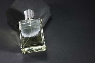 Photo of Stylish presentation of luxury men`s perfume in bottle on black background, space for text