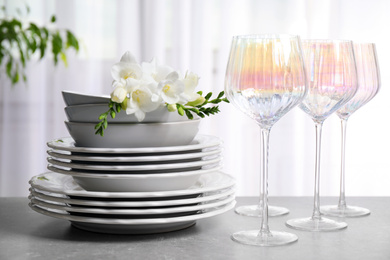 Set of glasses and dishes with flowers on light grey table