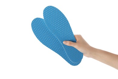 Photo of Woman holding pair of blue orthopedic insoles on white background, closeup