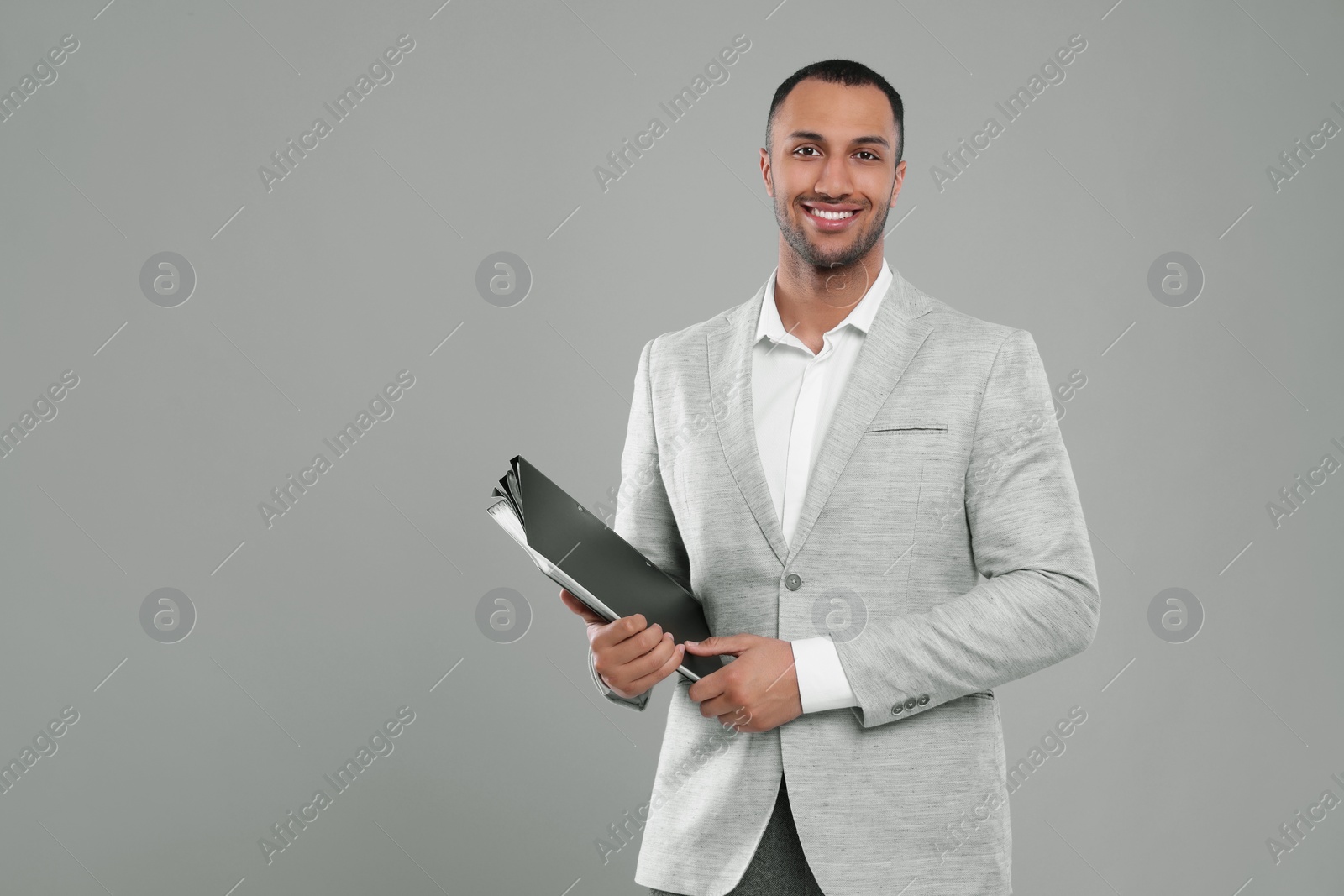 Photo of Young businessman with folders on grey background. Space for text