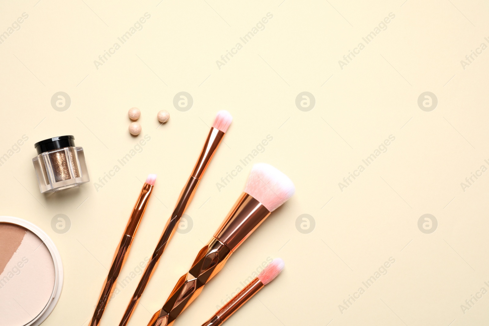 Photo of Flat lay composition with makeup brushes on beige background. Space for text