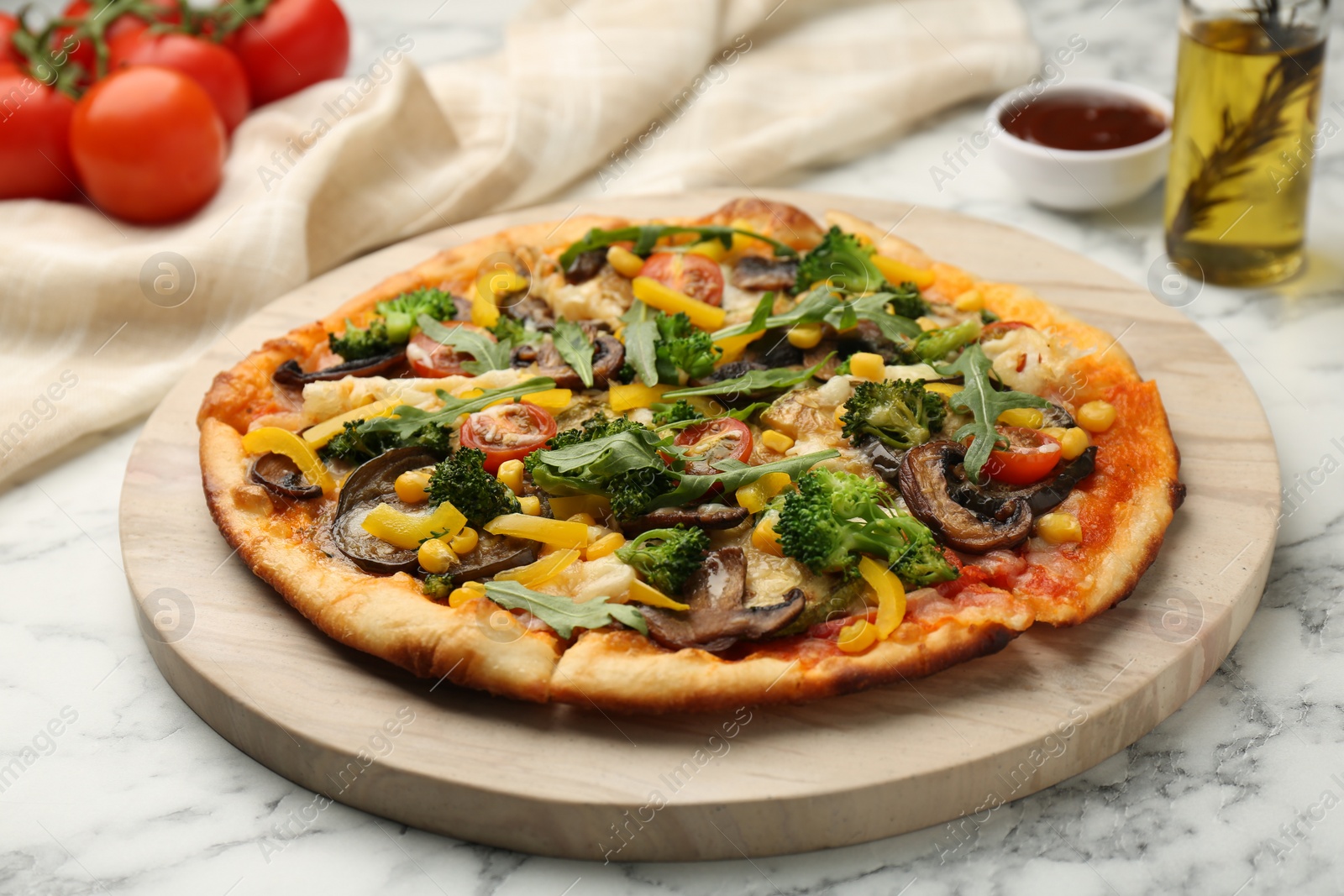 Photo of Delicious vegetarian pizza with mushrooms, vegetables and arugula on white marble table