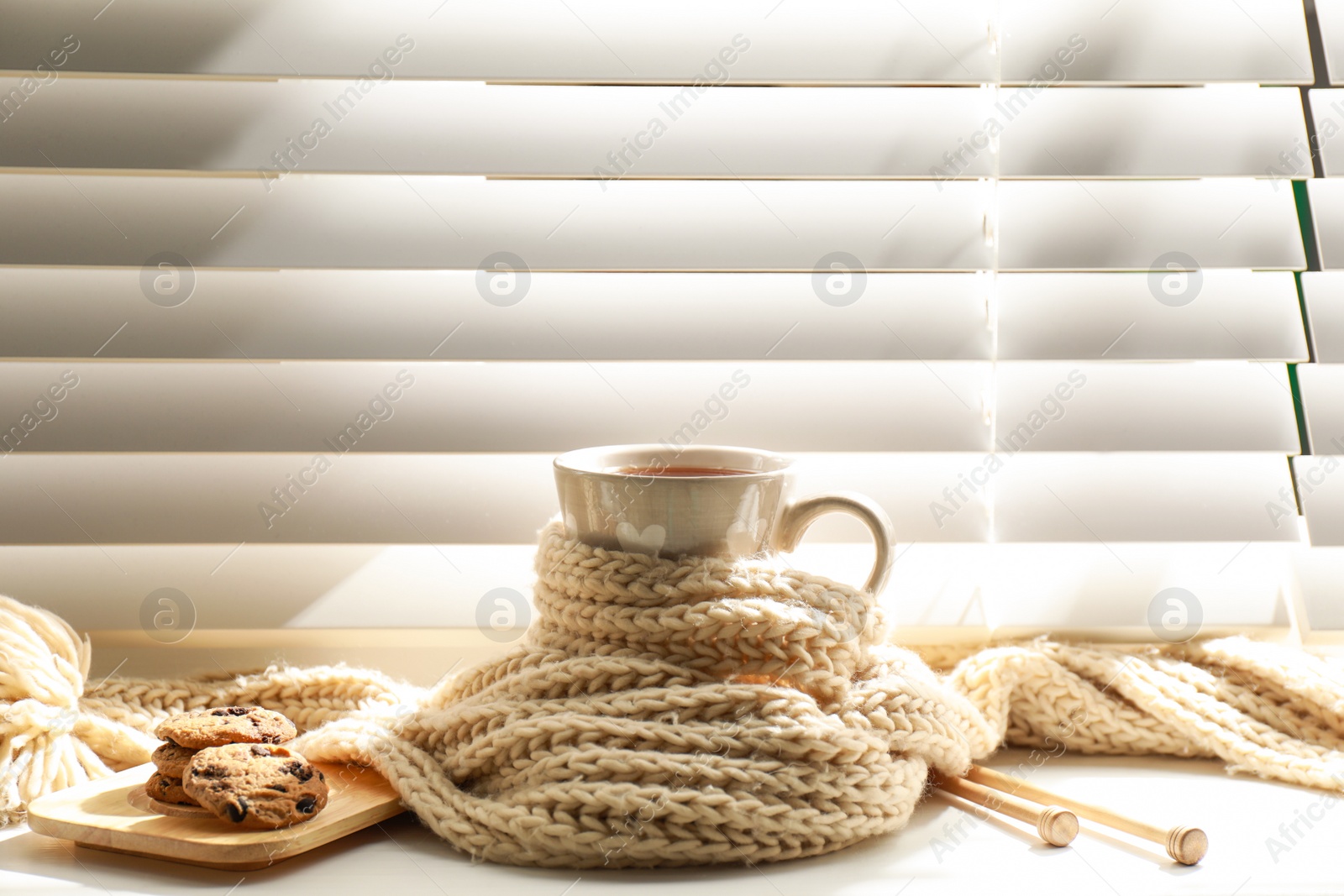 Photo of Cup of hot winter drink with scarf and cookies on windowsill indoors. Space for text