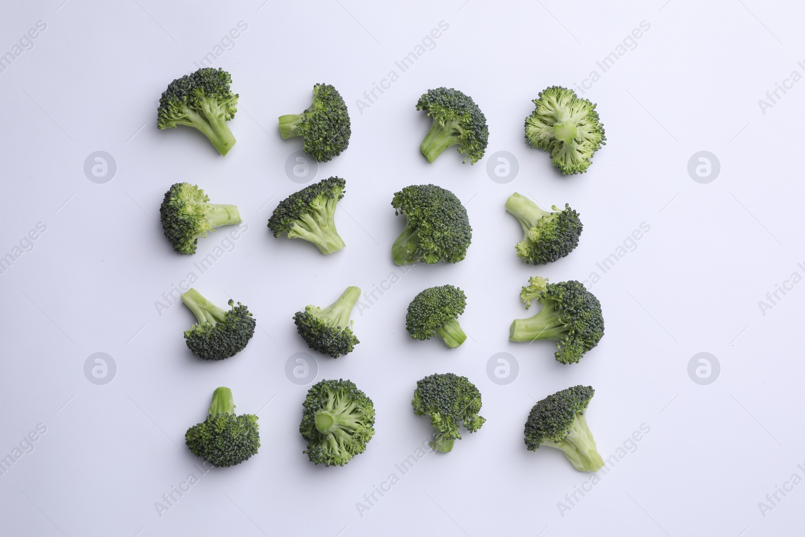 Photo of Many fresh green broccoli pieces on white background, flat lay