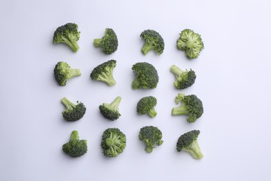 Many fresh green broccoli pieces on white background, flat lay