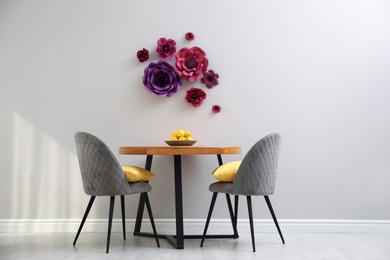 Dining table and chairs near wall with floral decor
