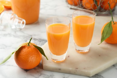 Delicious tangerine liqueur and fresh fruits on white marble table, closeup
