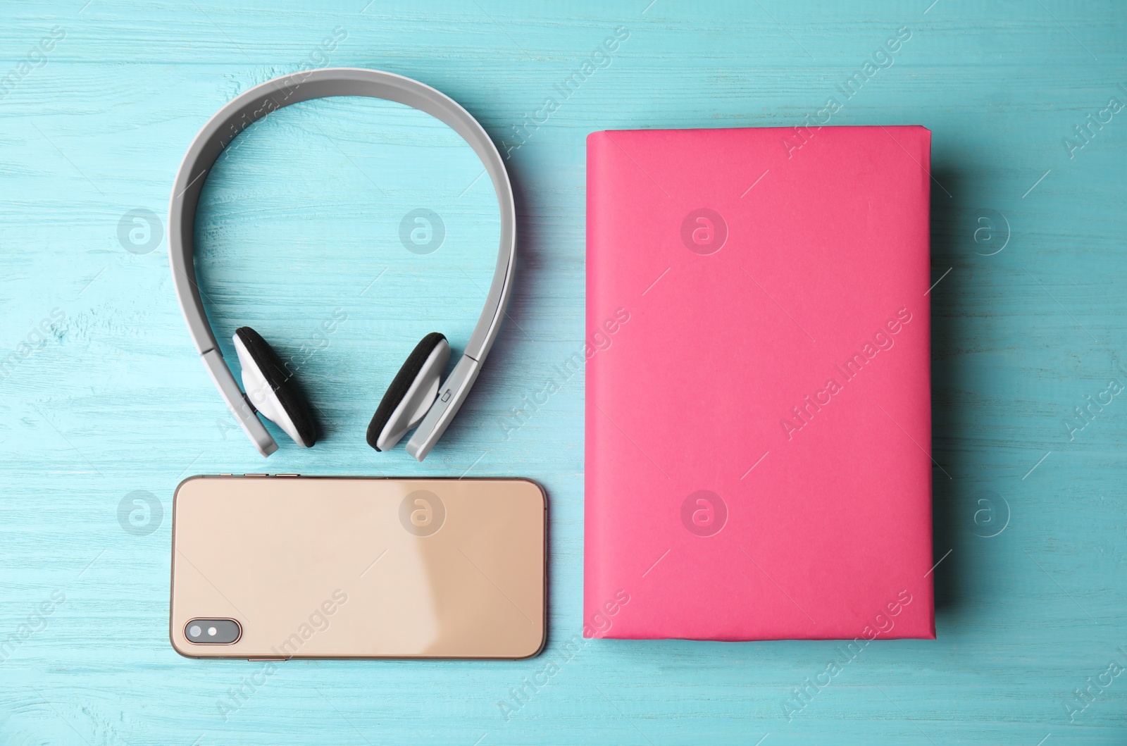 Photo of Book with mobile phone and headphones on light blue wooden background, flat lay