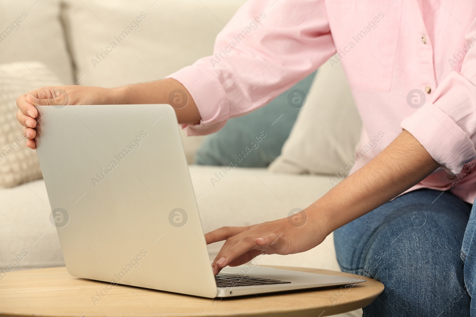 Photo of African American woman typing on laptop at table indoors, closeup