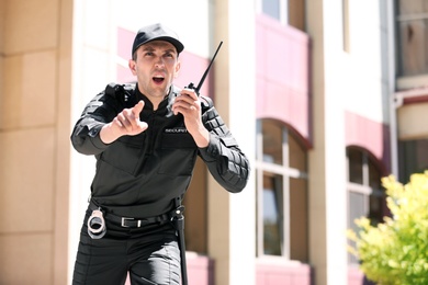 Male security guard using portable radio transmitter outdoors