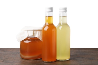 Delicious kombucha in glass bottles and jar on wooden table against white background