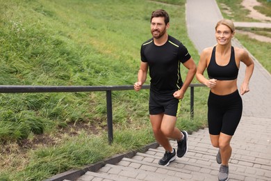 Photo of Healthy lifestyle. Happy couple running up stairs outdoors, space for text