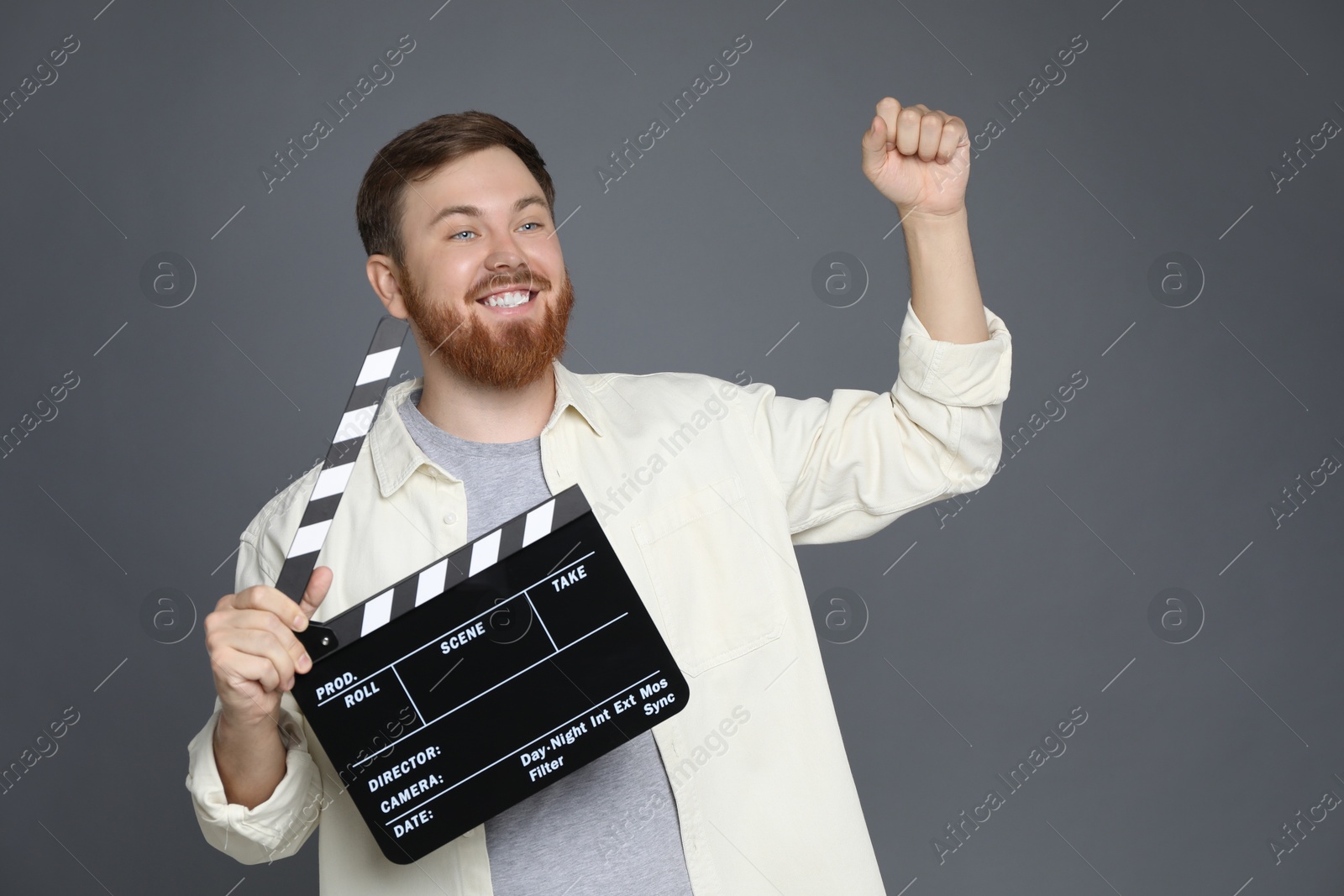 Photo of Making movie. Happy man with clapperboard on grey background