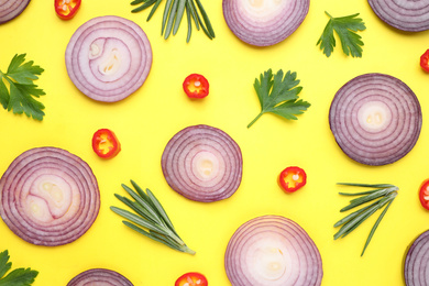 Flat lay composition with slices of onion and spices on yellow background