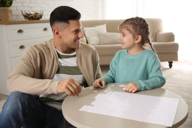 Photo of Happy father and his daughter playing with puzzles at home