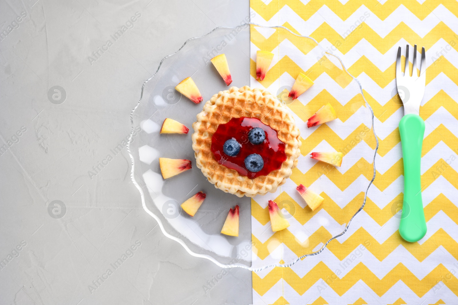 Photo of Tasty waffles served on grey table, flat lay. Creative idea for kids breakfast