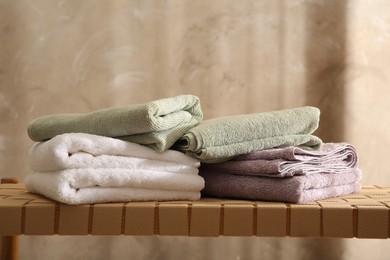 Photo of Stacks of soft towels on wicker bench indoors