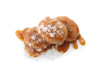 Photo of Yummy candies with caramel sauce and sea salt isolated on white, top view