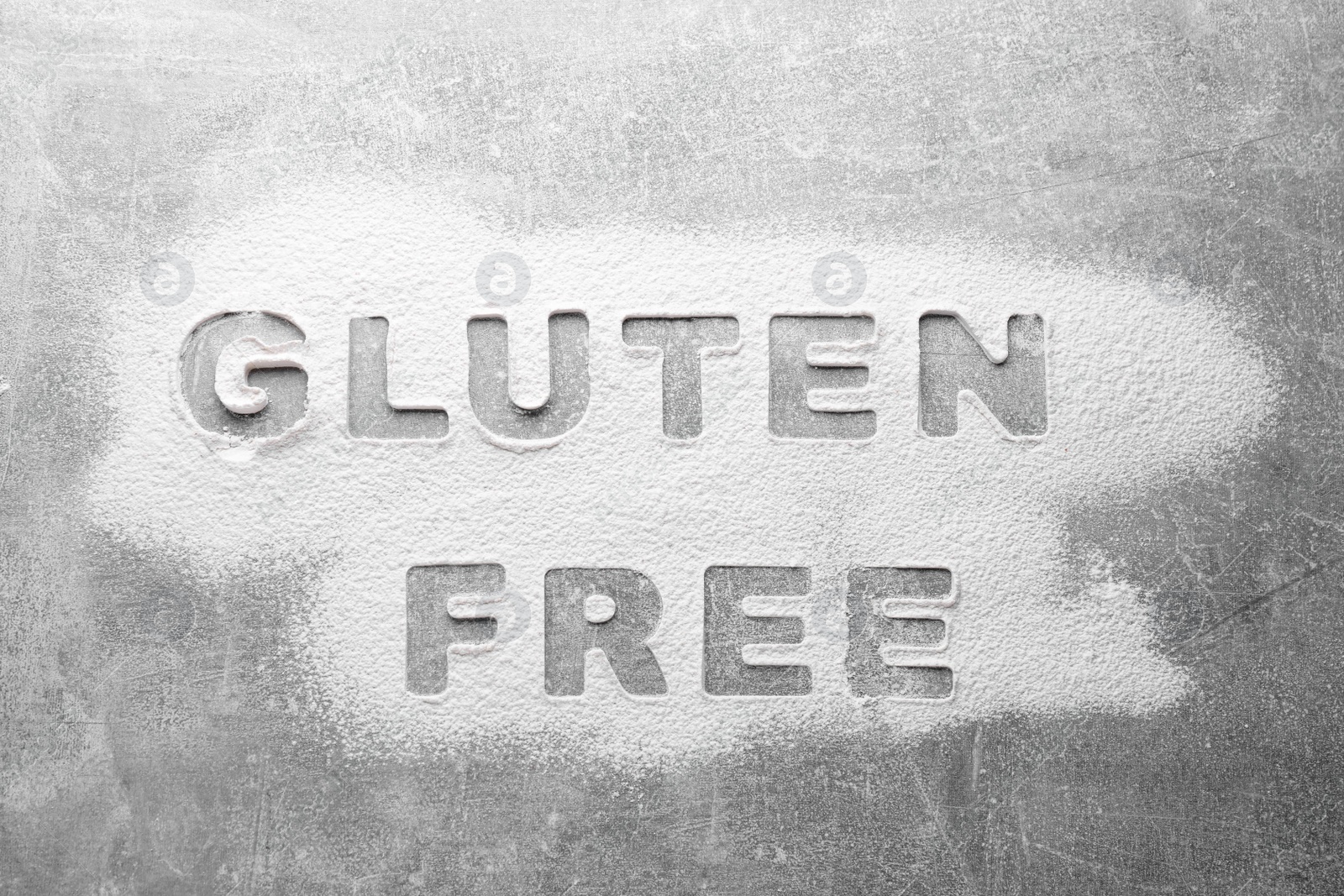 Photo of Words Gluten free written with flour on grey background, top view