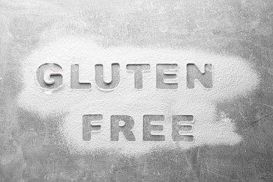 Photo of Words Gluten free written with flour on grey background, top view
