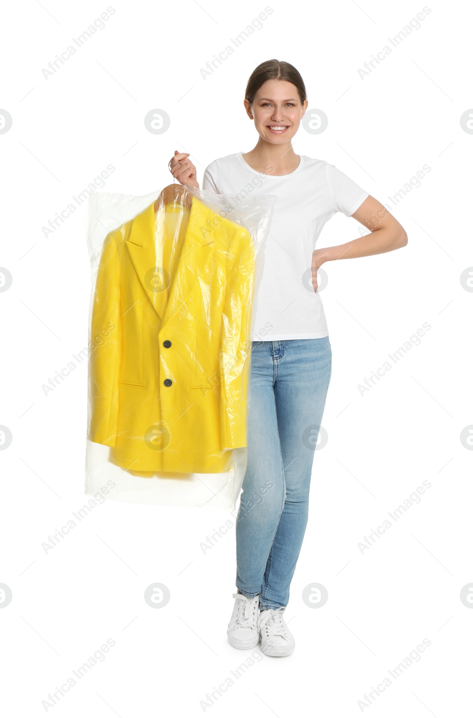 Photo of Young woman holding hanger with jacket in plastic bag on white background. Dry-cleaning service