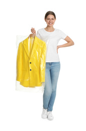 Photo of Young woman holding hanger with jacket in plastic bag on white background. Dry-cleaning service