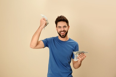 Photo of Portrait of happy young man with money on color background