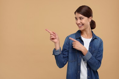 Photo of Special promotion. Happy woman pointing at something on beige background, space for text