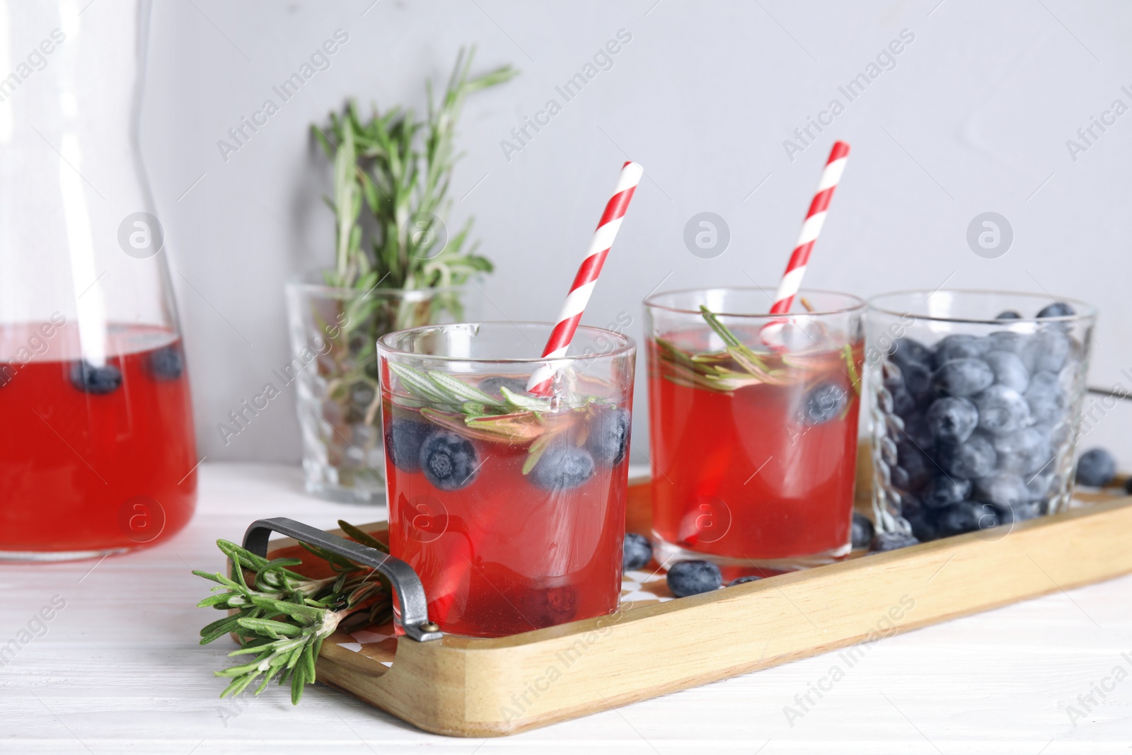Photo of Tasty refreshing blueberry cocktail with rosemary on table