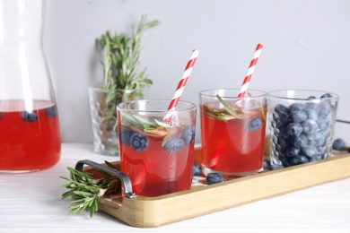 Photo of Tasty refreshing blueberry cocktail with rosemary on table