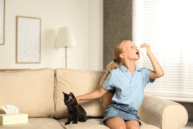 Photo of Little girl with cat suffering from allergy at home