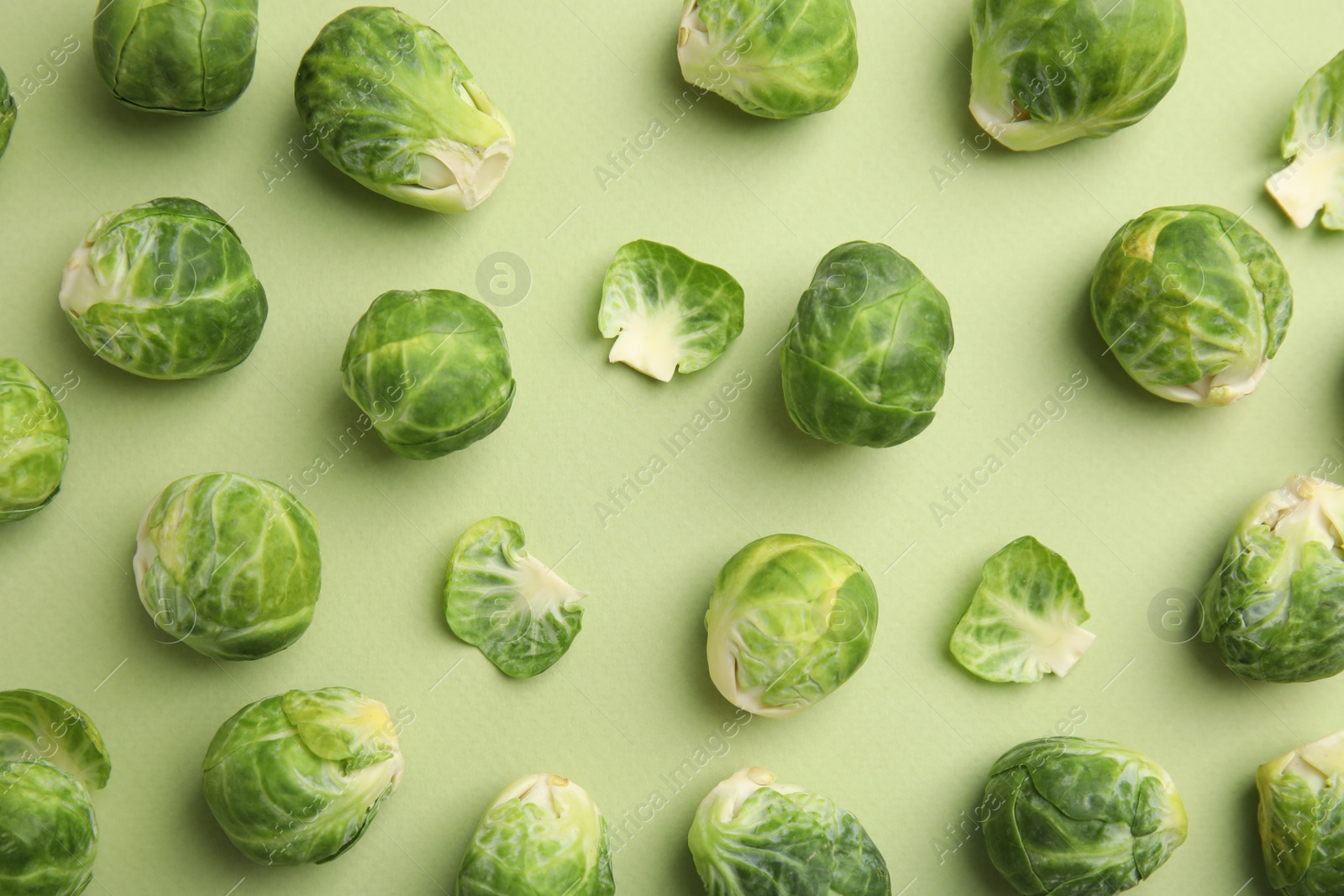 Photo of Fresh Brussels sprouts on green background, flat lay