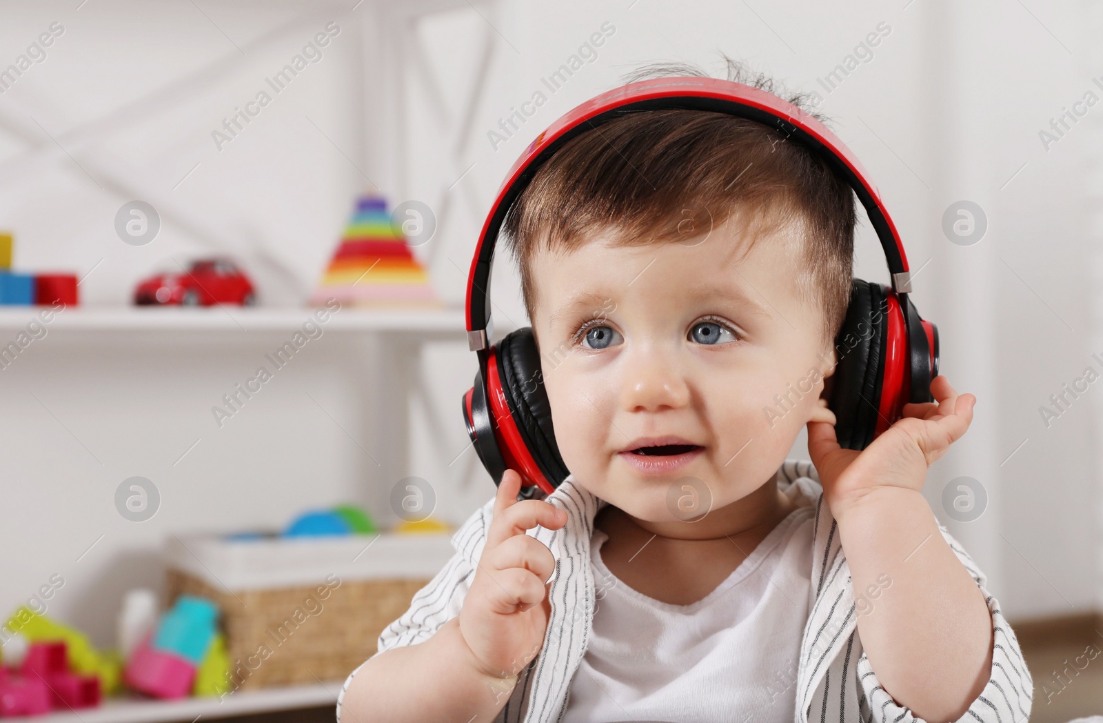 Photo of Cute little boy in headphones listening to music at home, space for text