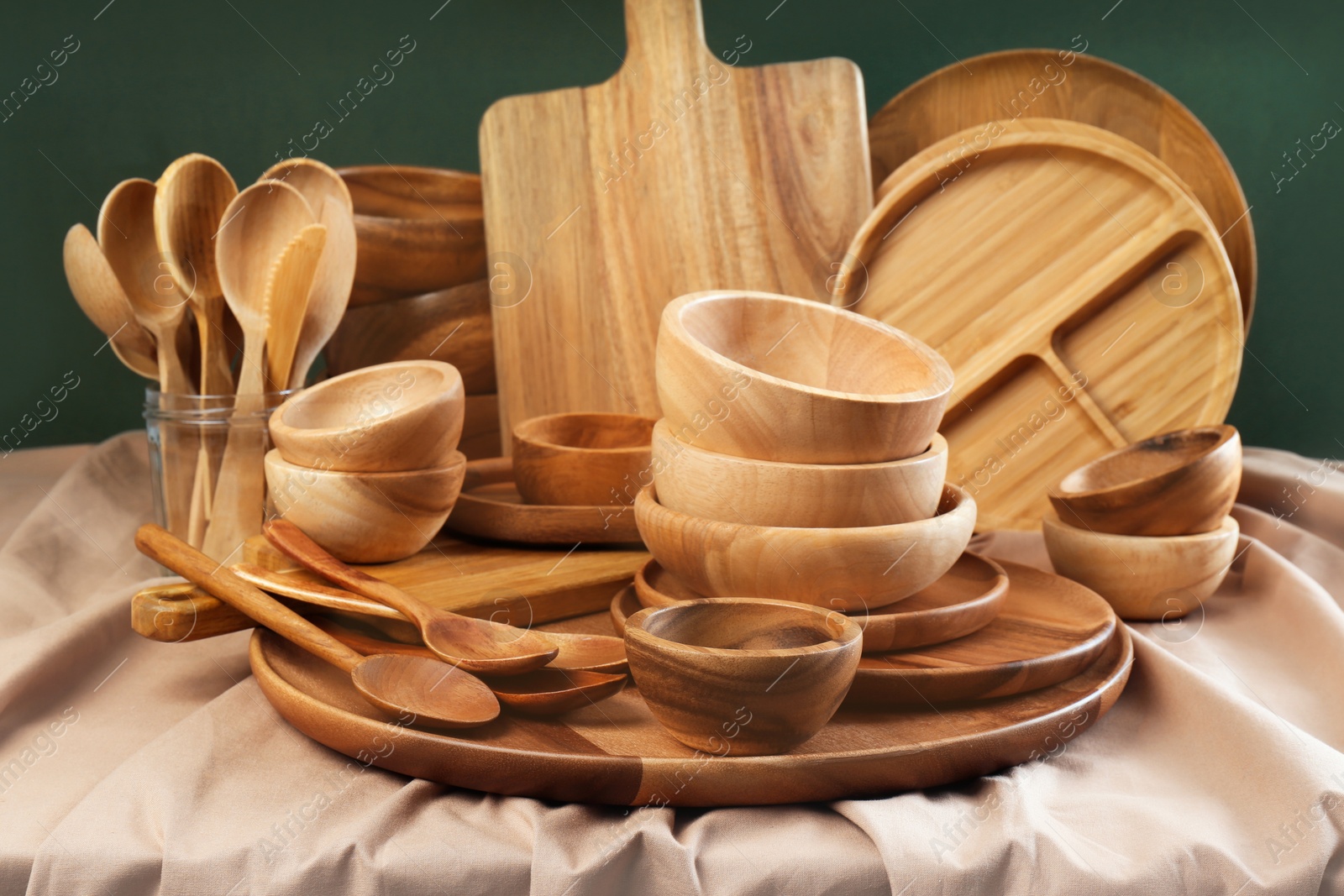 Photo of Set of wooden dishware and utensils on table against green background