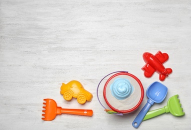 Flat lay composition with beach toys on white wooden background. Space for text