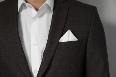 Photo of Man with handkerchief in breast pocket of his suit on light grey background, closeup