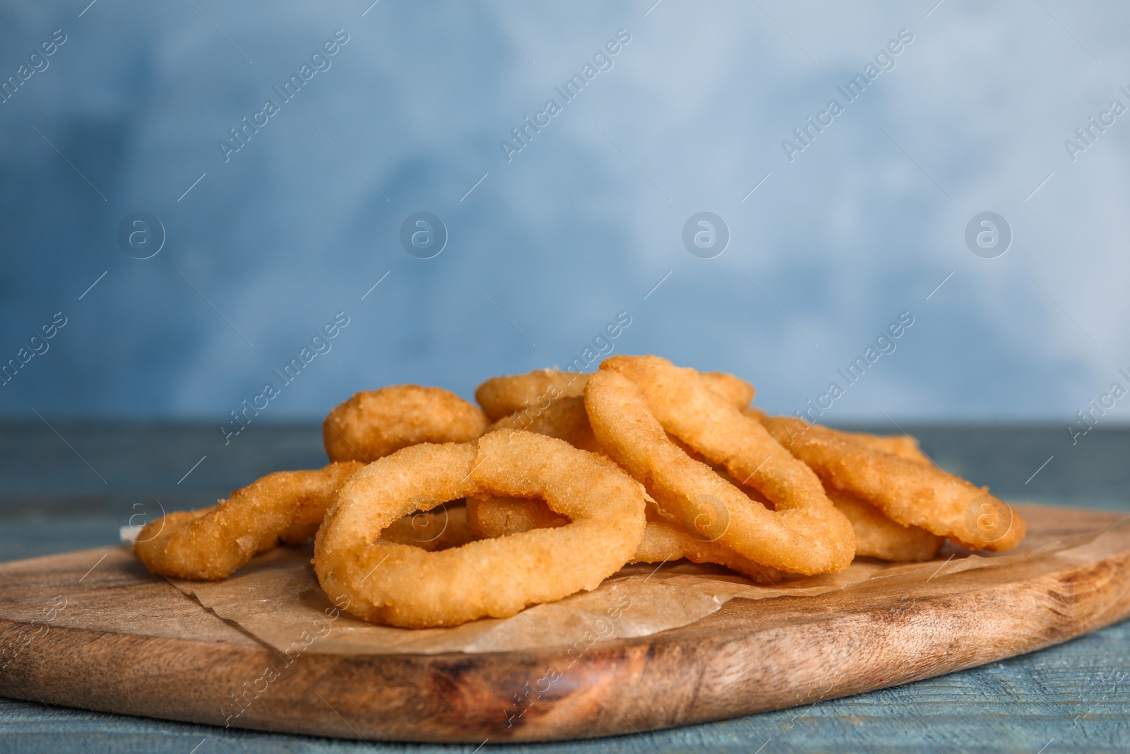 Photo of Fried onion rings served on blue wooden table