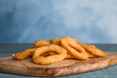 Photo of Fried onion rings served on blue wooden table