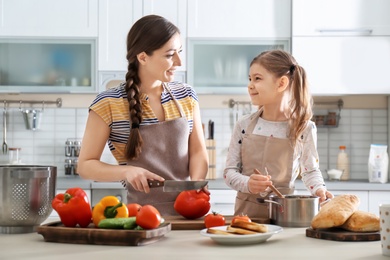 Photo of Young nanny with cute little girl cooking together in kitchen