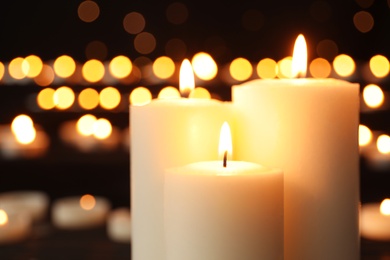 Photo of Burning candles on dark background with blurred lights