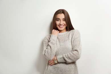 Beautiful young woman in warm sweater on white background