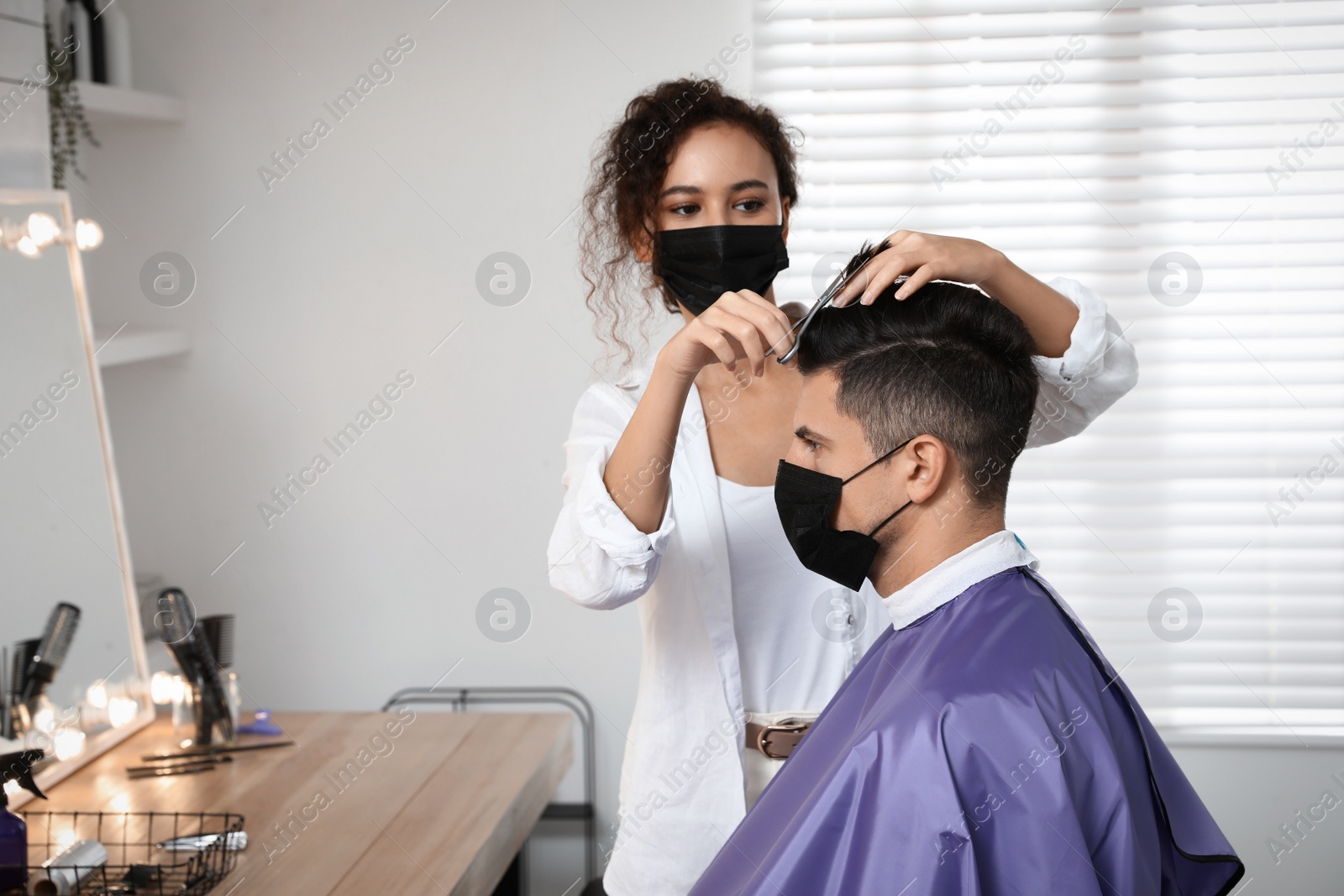 Photo of Professional stylist working with client in salon. Hairdressing services during Coronavirus quarantine