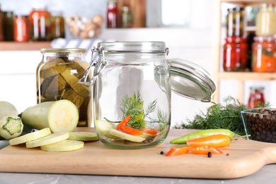 Photo of Jar with zucchini and dill on grey marble table indoors. Pickling vegetables