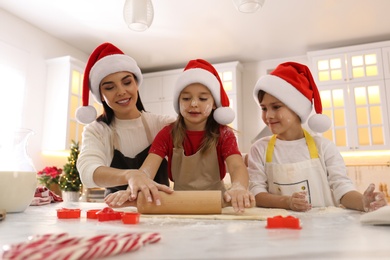 Mother and her cute little children making Christmas cookies in kitchen