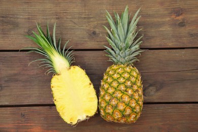 Whole and cut ripe pineapples on wooden table, flat lay