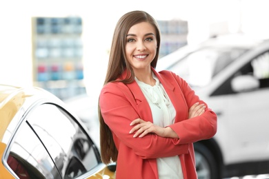 Photo of Young woman standing near car in salon