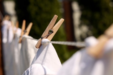 Photo of Clean clothes drying outdoors, closeup. Focus on clothespin