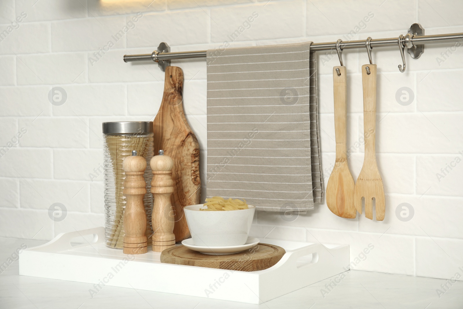 Photo of Clean towel, utensils and uncooked pasta in kitchen