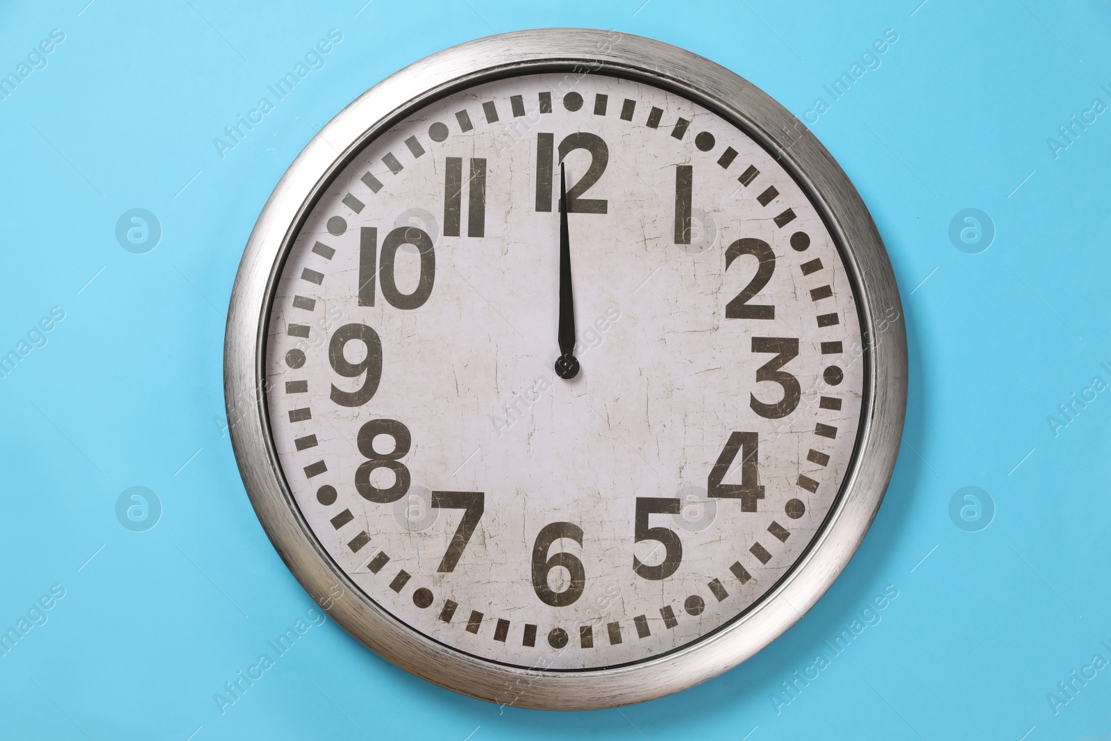 Photo of Stylish analog clock hanging on light blue wall